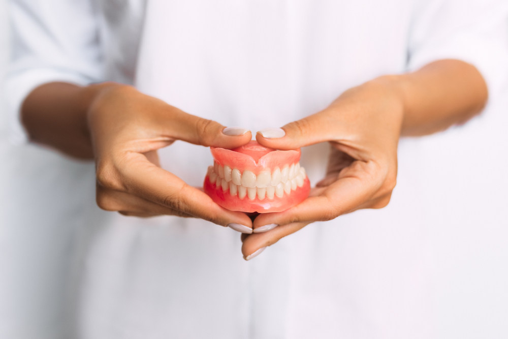 Dentist Holding Dentures (dentures for missing teeth)